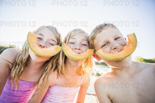 Caucasian children eating cantaloupe slices