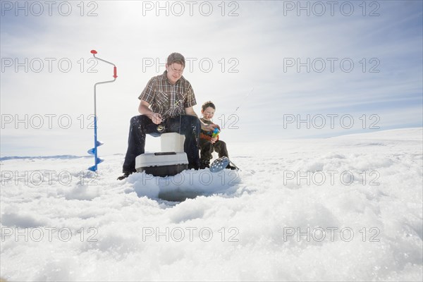 Caucasian father and son ice fishing