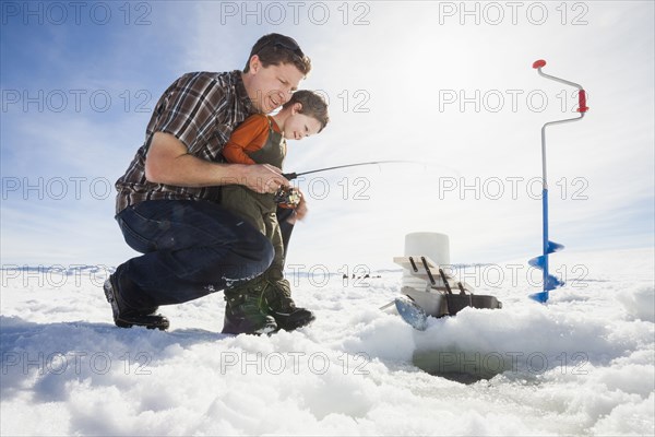 Caucasian father and son ice fishing