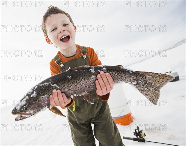 Caucasian boy holding fish in snow