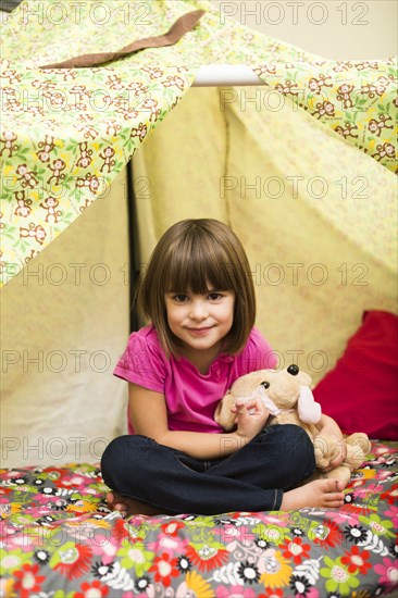 Caucasian girl sitting in blanket fort