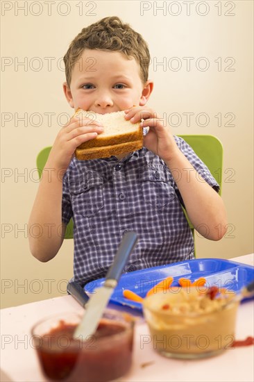 Caucasian boy eating sandwich in kitchen
