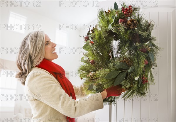 Caucasian woman hanging Christmas wreath on door