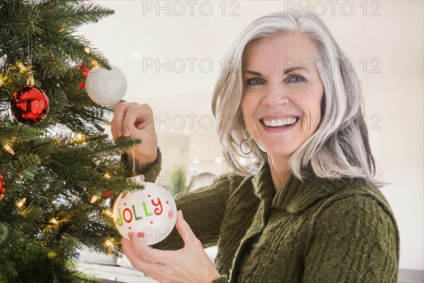 Portrait of Caucasian woman hanging ornaments on Christmas tree