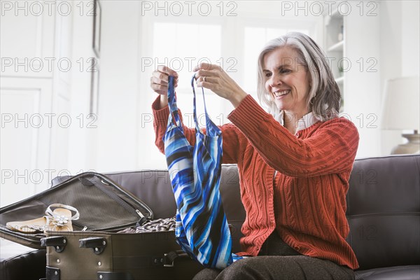 Caucasian woman packing bathing suit in suitcase