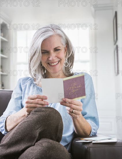 Happy Caucasian woman reading card on sofa