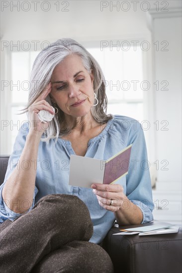 Serious Caucasian woman reading card on sofa