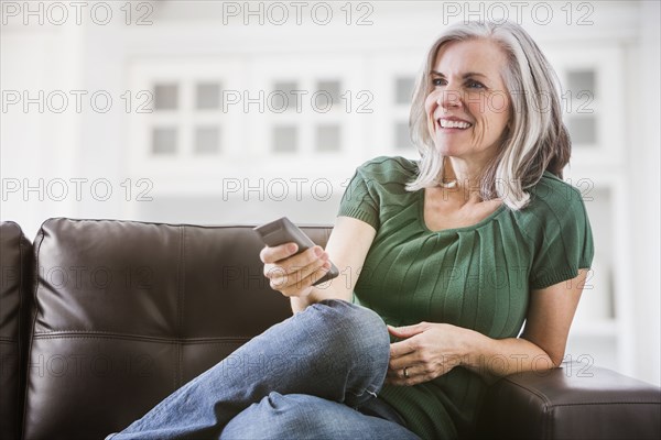 Happy Caucasian woman watching TV on sofa