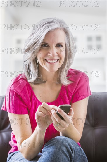 Portrait of smiling Caucasian woman text messaging on sofa