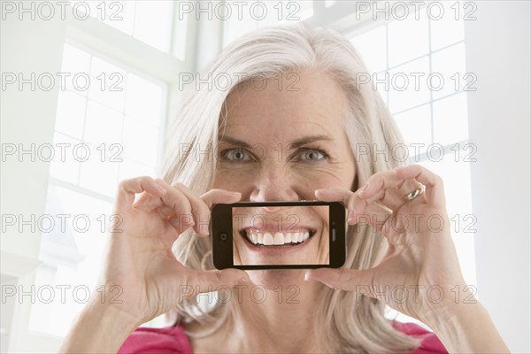 Caucasian woman holding cell phone with image of smile