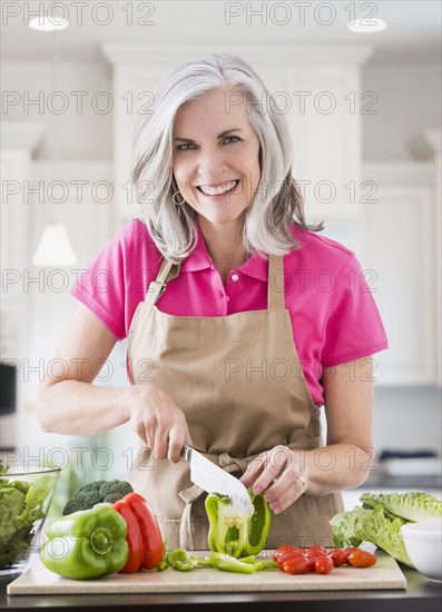 Portrait of smiling Caucasian woman slicing vegetables