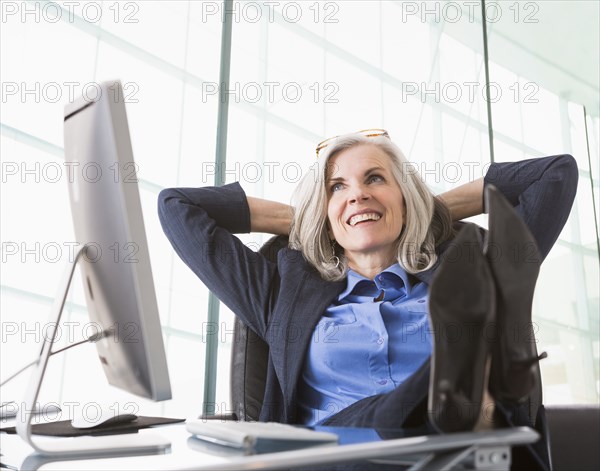 Confident Caucasian businesswoman with feet up on desk