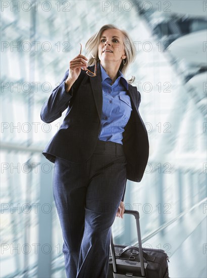 Caucasian businesswoman rushing with suitcase in airport