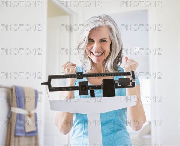 Excited Caucasian woman cheering on weight scale