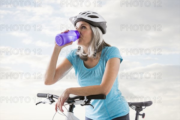 Caucasian woman drinking from water bottle on bicycle