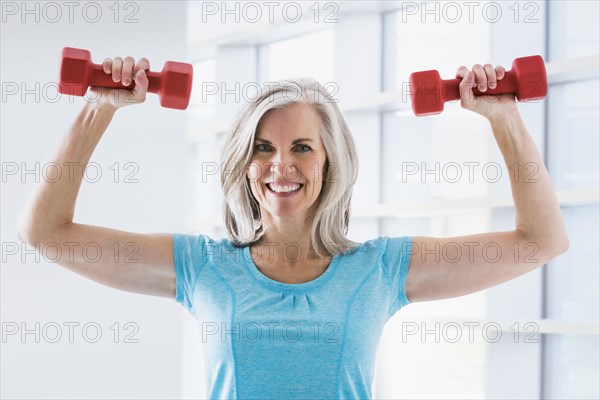 Portrait of confident Caucasian woman lifting dumbbells
