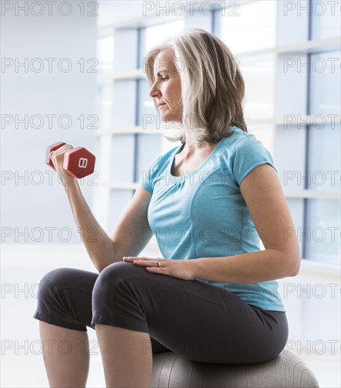 Caucasian woman doing biceps curls with dumbbell