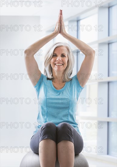 Portrait of happy Caucasian woman balancing on fitness ball