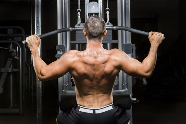 Caucasian man with bare chest lifting weights on machine