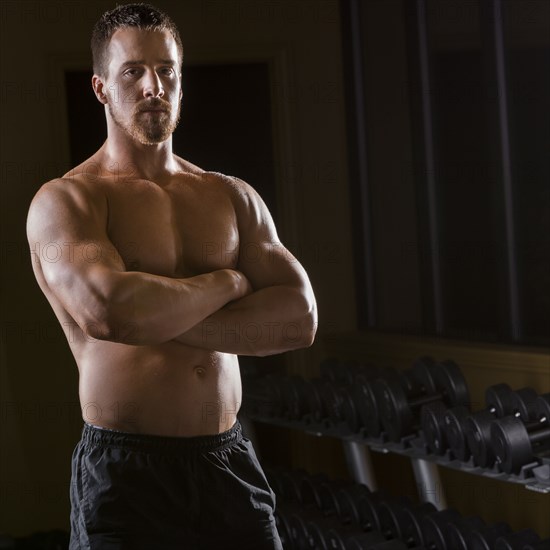 Portrait of confident Caucasian man with bare chest in gym