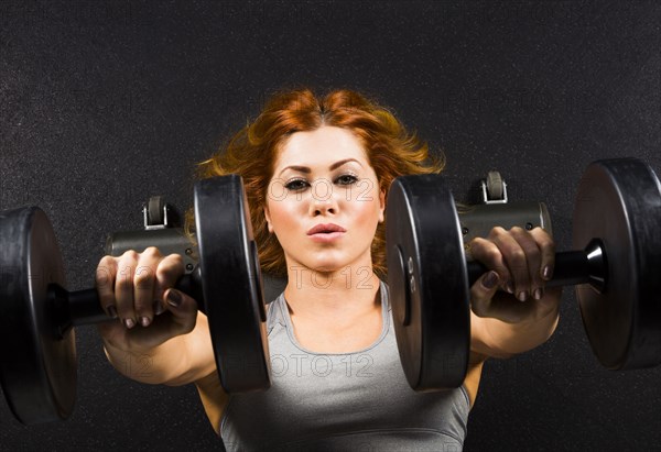 Caucasian woman doing chest presses with dumbbells in gym