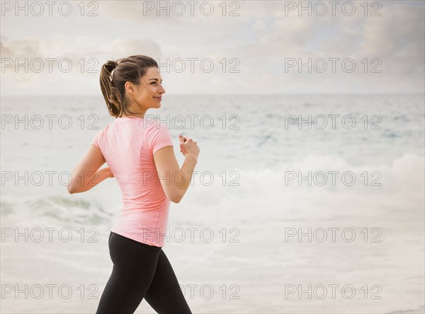 Caucasian woman running on beach