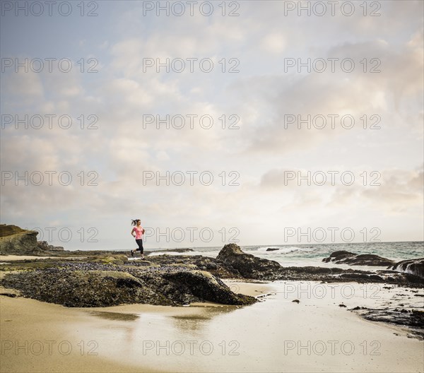 Caucasian woman running on beach