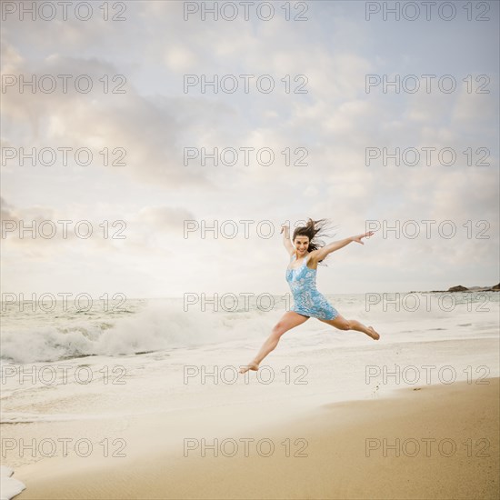 Caucasian woman jumping on beach