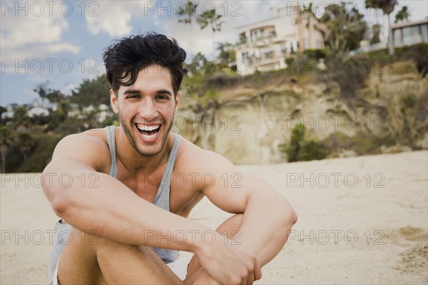 Caucasian man sitting on beach