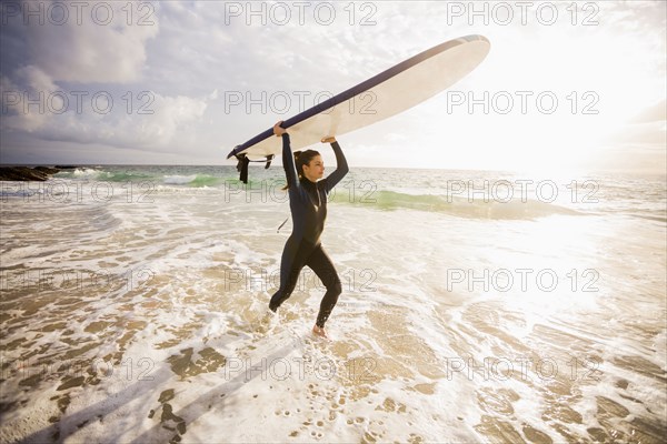 Caucasian surfer carrying board in waves