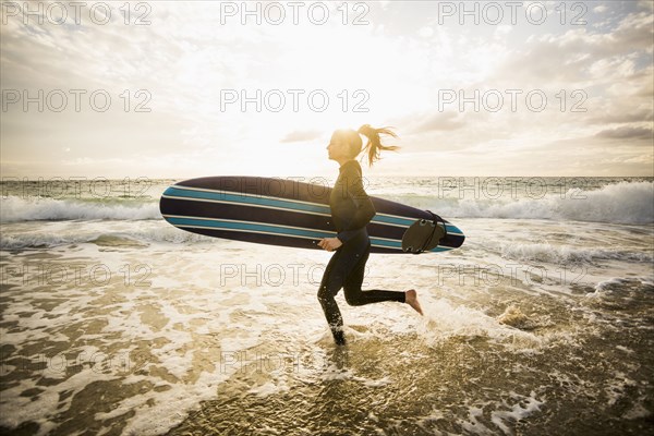 Caucasian surfer carrying board in waves