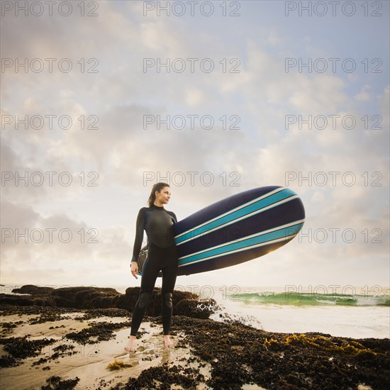 Caucasian surfer carrying board on beach