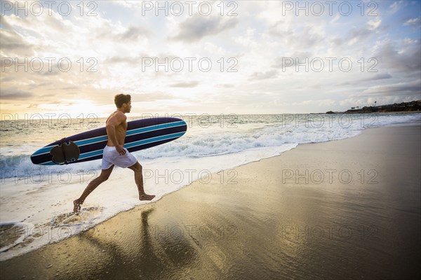 Caucasian surfer carrying board in waves