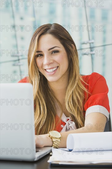 Mixed race businesswoman smiling at desk