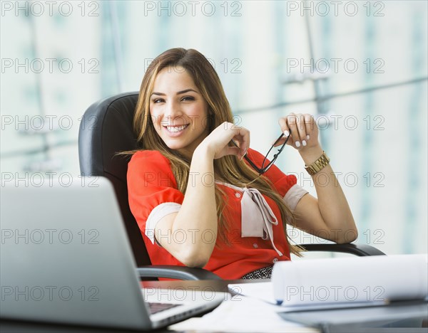 Mixed race businesswoman smiling at desk