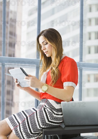 Mixed race businesswoman using digital tablet at desk
