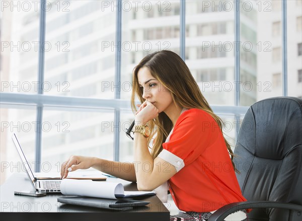 Mixed race businesswoman working at desk