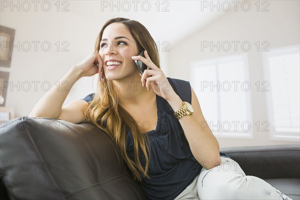 Mixed race woman talking on cell phone on sofa