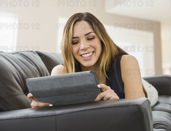 Mixed race woman using digital tablet on sofa