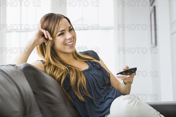 Mixed race woman watching television on sofa