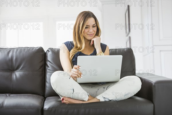 Mixed race woman using laptop on sofa