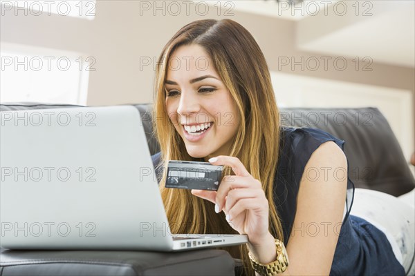 Mixed race woman shopping online on sofa