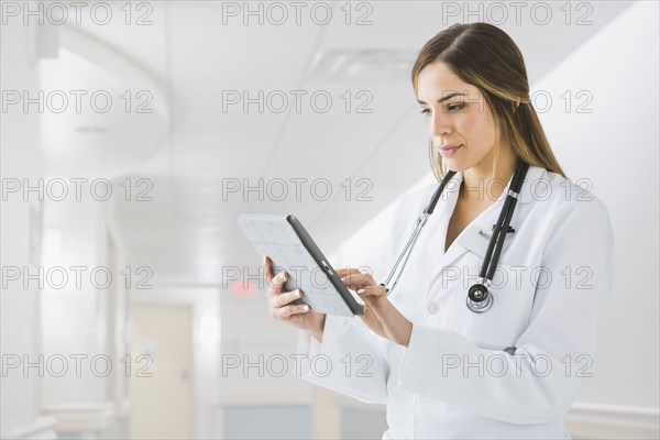 Mixed race doctor using digital tablet in hospital