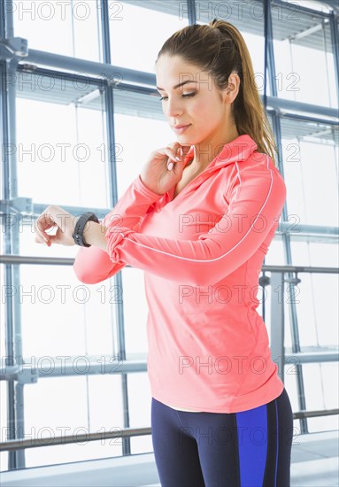 Mixed race woman checking pulse in gym