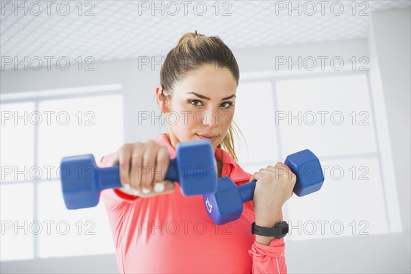 Mixed race woman lifting weights in gym