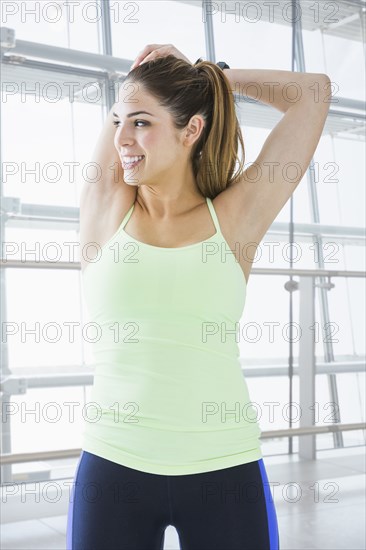 Mixed race woman stretching in gym