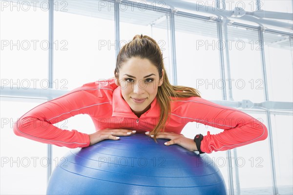 Mixed race woman using exercise ball in gym