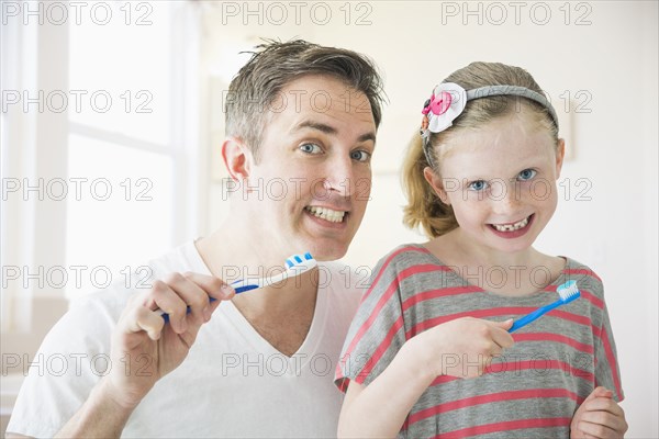 Caucasian father and daughter brushing their teeth