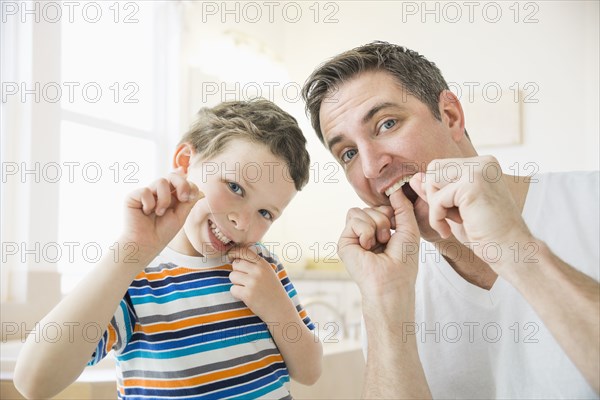 Caucasian father and son flossing their teeth
