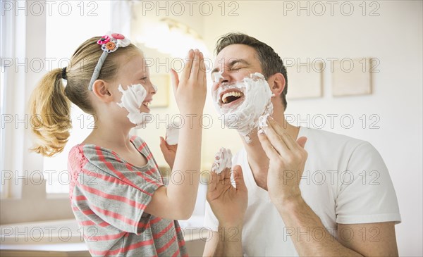 Caucasian father and daughter playing with shaving cream